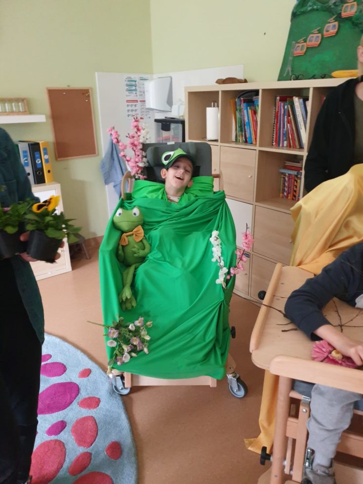 Na fotografii chłopiec na wózku przebrany za zieloną żabkę.