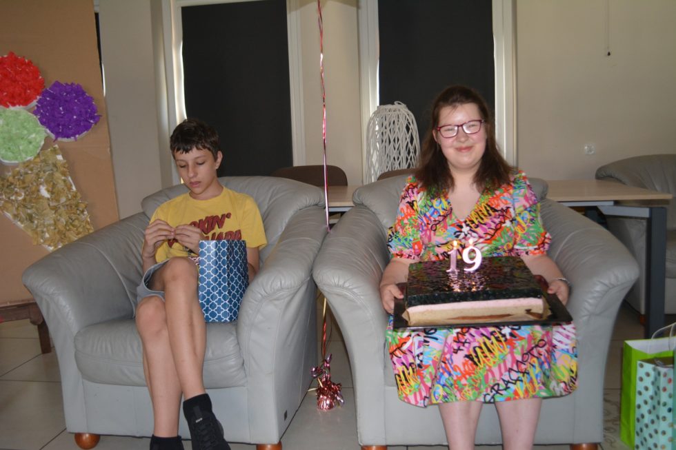 Na fotografii Emilka z tortem na fotelu, obok Mateusz na fotelu odwijający cukierka.