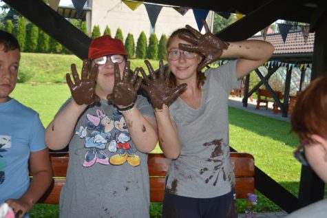 Na fotografii dwie dziewczynki pokazujące ręce ubrudzone farbą podczas zajęć sensorycznych.