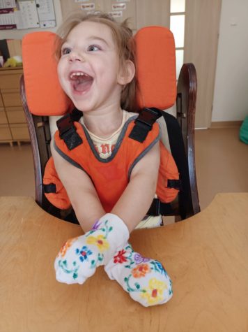 Na fotografii Daria z założonymi kolorowymi skarpetkami na rączkach.