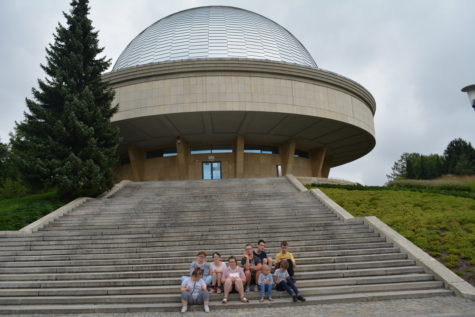 Na zdjęciu uczniowie siedzą na schodach w tle Planetarium Śląskie w Chorzowie.