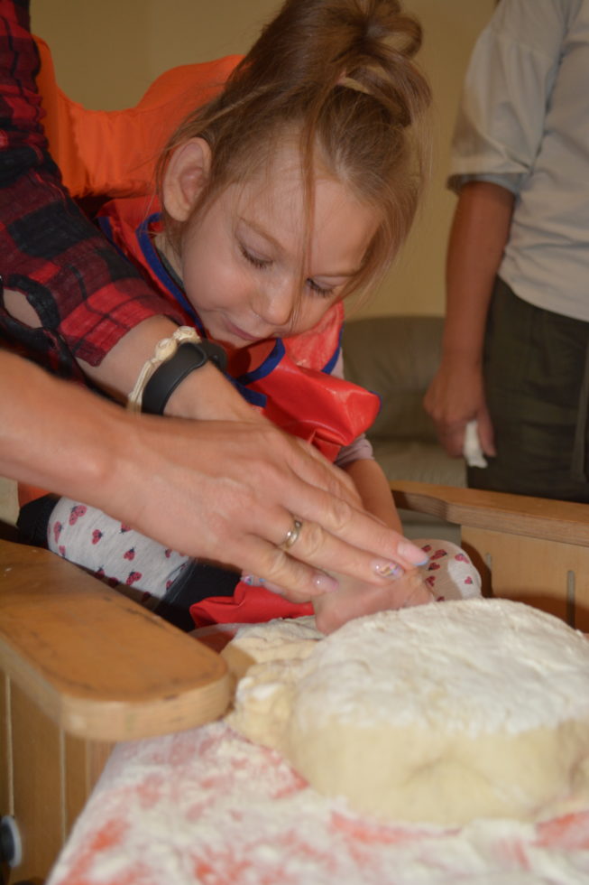 Na fotografii Daria z pomocą opiekuna ugniata ciasto na pizzę.