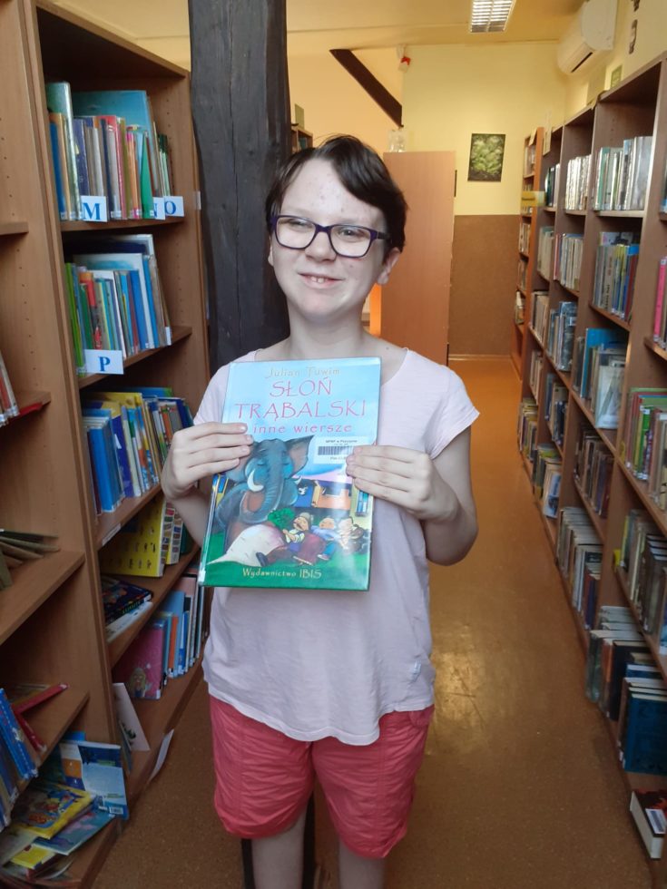 Na zdjęciu Irenka z książką w bibliotece.