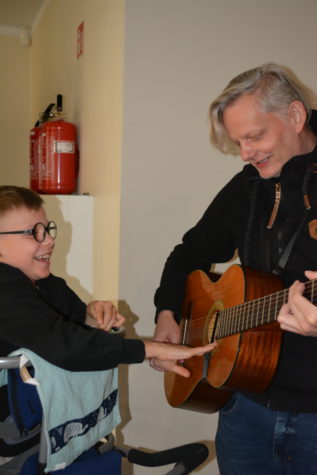 Na zdjęciu Pan Sebastian gra na gitarze a chłopiec dotyka strun.