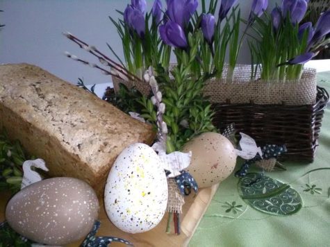 Na zdjęciu dekoracja na Święta Wielkanocne, palemka, jajka, krokusy, chleb, gąski na stole.