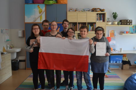 Na fotografii uczniowie stoją trzymając flagę Polski oraz list od Pana Burmistrza.