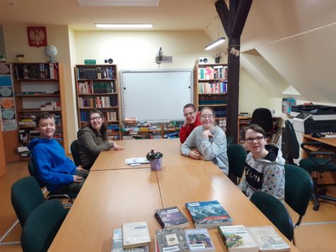 Na zdjęciu uczniowie siedzą przy stole w bibliotece w trakcie zajęć.