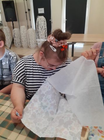Na fotografii Agatka rozwarstwia serwetkę, którą ozdobi drewnianą skrzynkę.