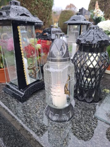 Na zdjęciu kawałek pomnika ze zniczami w szarych kolorach na cmentarzu.