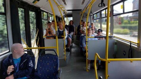 Na zdjęciu wnętrze autobusu miejskiego, chłopcy i dziewczynki oraz opiekunowie siedzą na siedzeniach i jadą na wycieczkę.