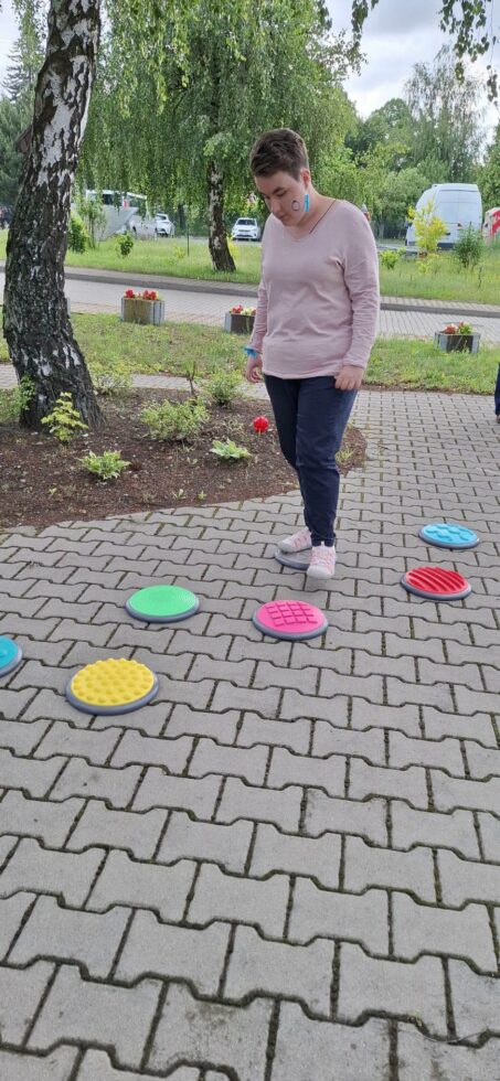 Na zdjęciu kobieta idzie po kolorowych gumowych kołach o różnej fakturze.